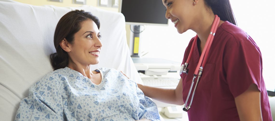 Nurse Talking To Female Patient In Hospital Room